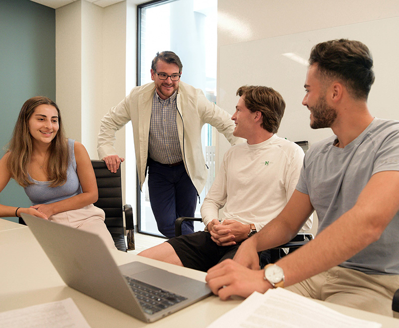 Three sitting students with an instructor standing behind them