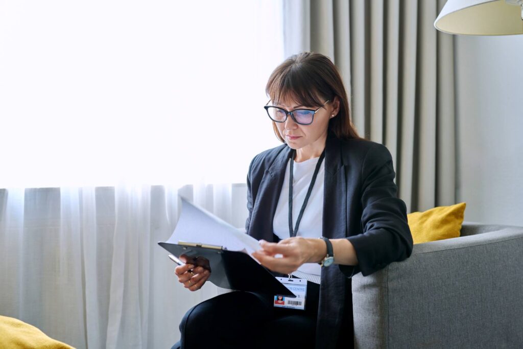 Social worker sitting in an office looking at paperwork on a clipboard