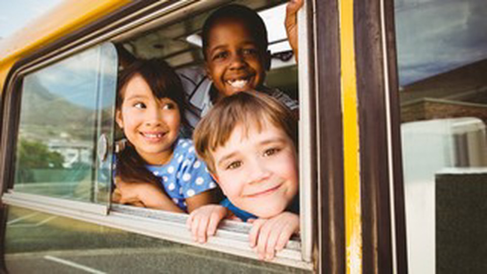 Three children on a school bus window