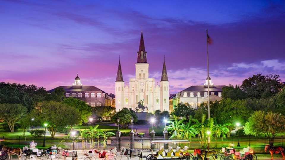 New Orleans buildings with horse drawn carriages in the foreground at dusk