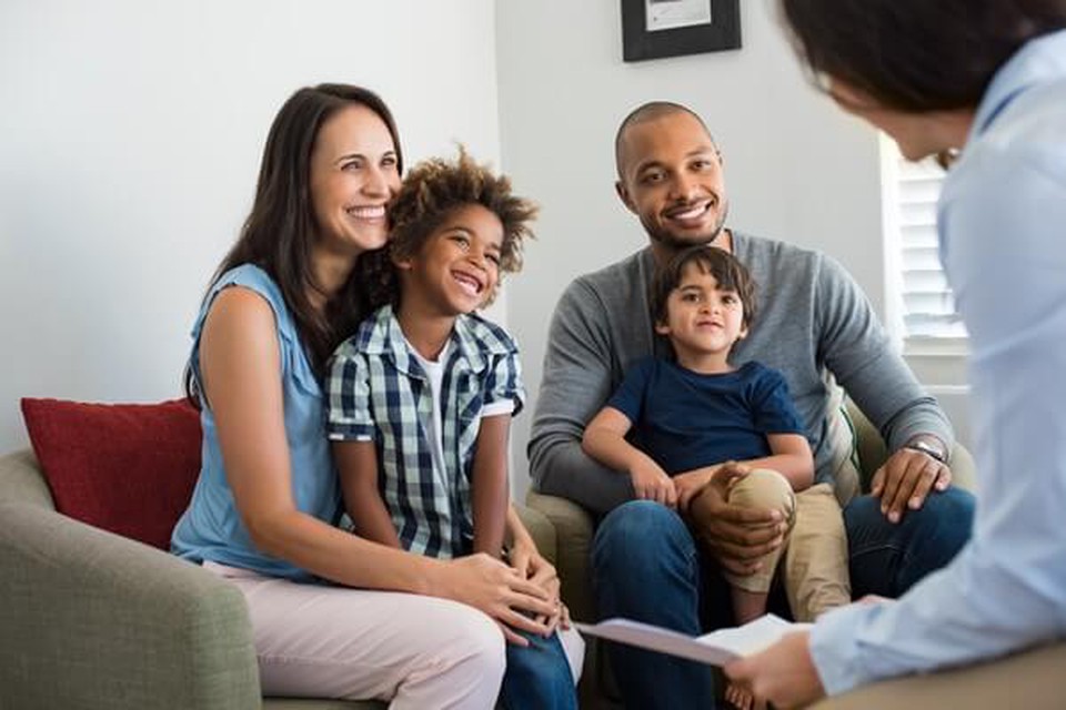 A woman, man and two children seated at a counselor's office