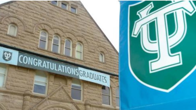A brown building in the background with a Congratulations Graduates banner hanging on it with a Tulane University banner in the foreground