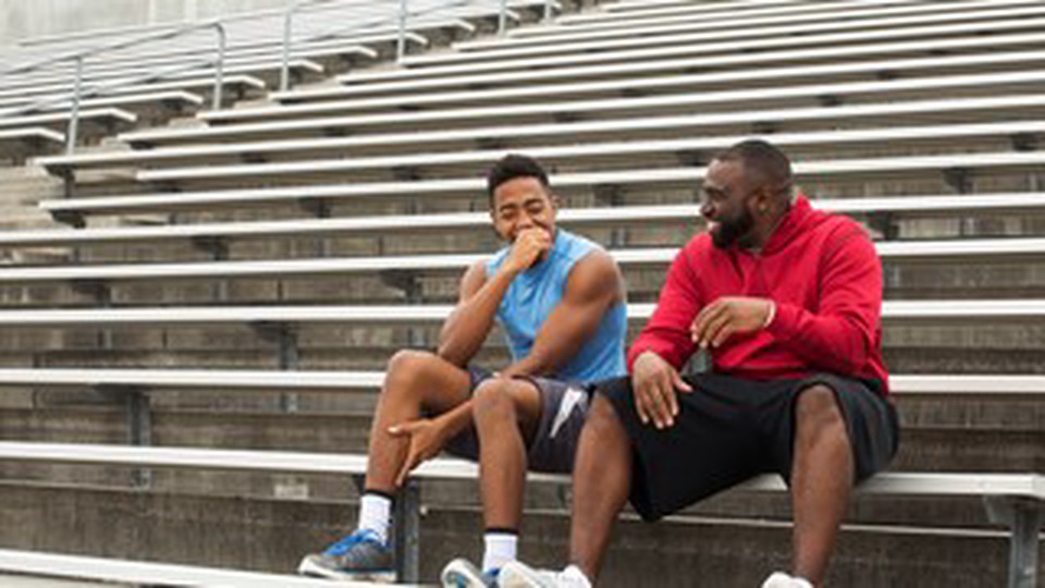 Two man with athletic clothes seated on the bleachers
