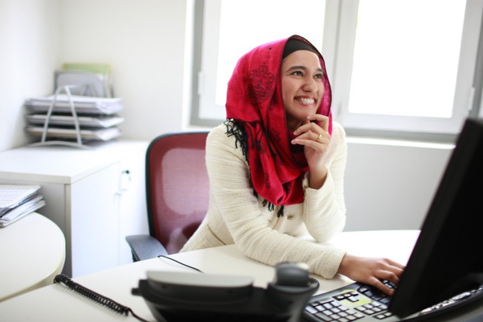 An inspired social worker smiles while reading an inspirational quote on the computer.