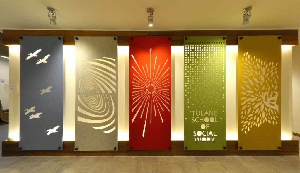 Colorful and backlit banners hang a Tulane School of Social Work building