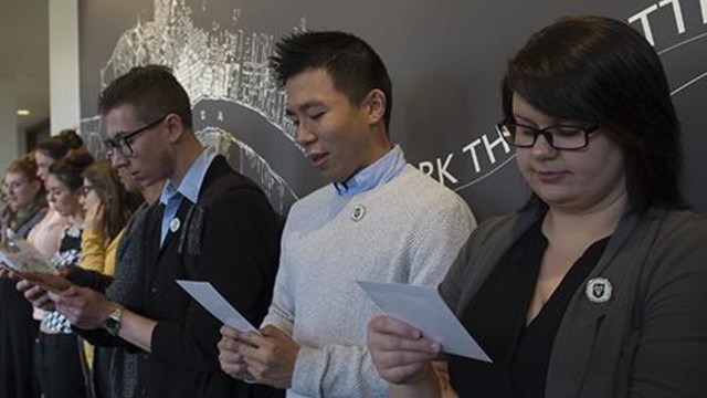 A group of Tulane social work students stand against a wall and read together from white cards