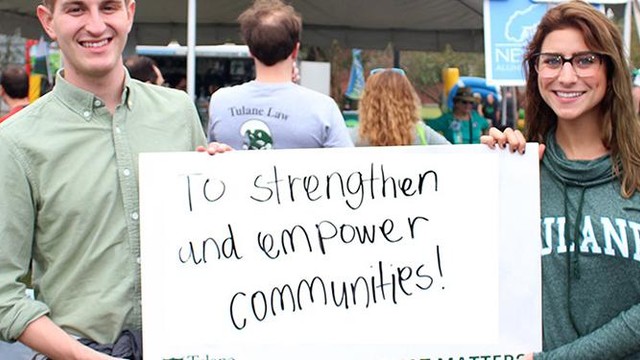Two Tulane University students hold a handwritten sign encouraging others to empower communities