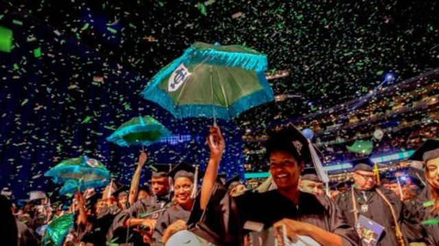 Graduate hold up blue and green umbrellas during a Tulane University graduation ceremony with confetti in the air