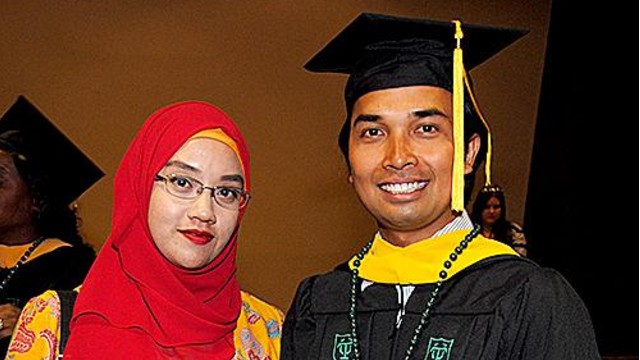 A Tulane University MSW student wearing a cap and gown stands with his partner