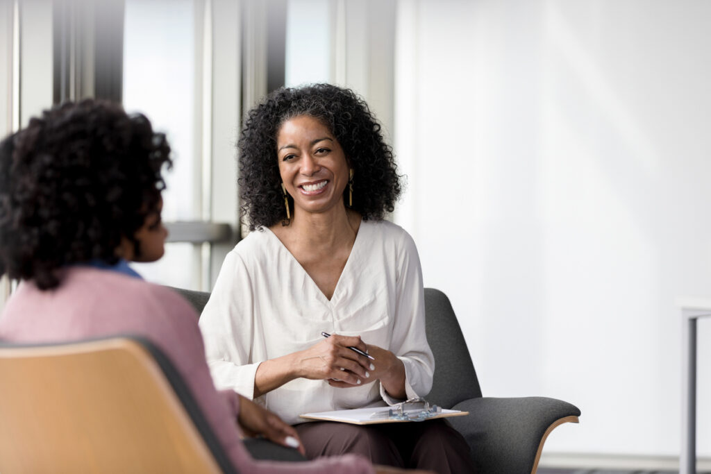 A clinical social worker meets with a client in an office.