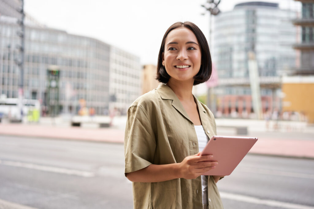 A city planner standing by a downtown street holding a tablet device.