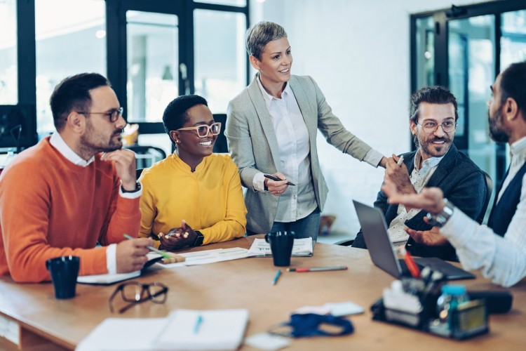 A social work leader conducts a team discussion around a conference table.